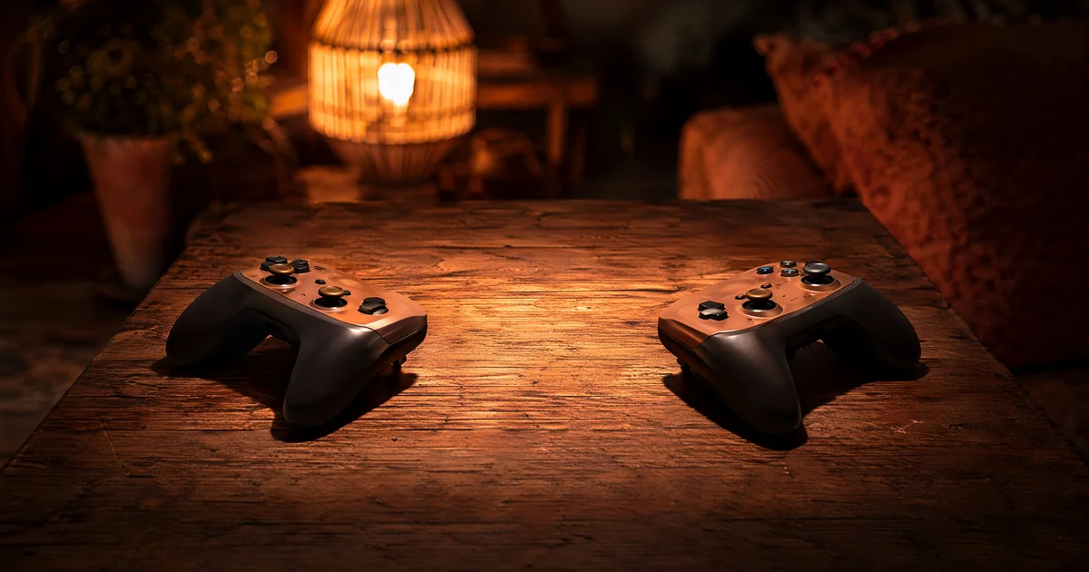 対戦・格闘ゲームTOP3のヘッダー画像。木のテーブルの上で2つのゲームコントローラーが向かい合わせに置かれ、ランタンの光が対決前の雰囲気を照らす。